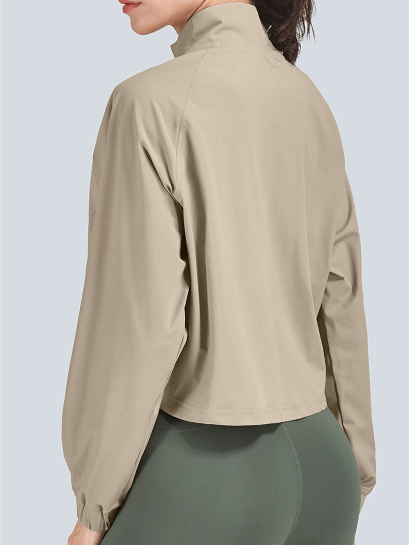 Back view of women's beige stand collar short jacket, ideal for casual sports. Features a loose fit with zipper closure, model in green leggings.